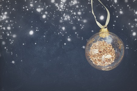 Golden christmas ball on black wooden background with snowの写真素材