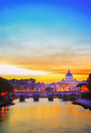 St. Peter's cathedral over bridge and river in Rome at orange sunset, Italyの写真素材