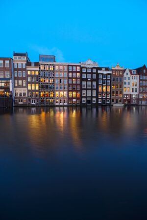 Houses facades over canal with reflections illuminated at blue night, Amsterdam, Netherlandsの写真素材