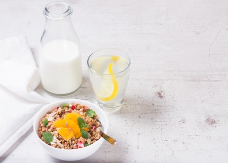 Healthy breakfast - plate of granola with orange slices, mint and seeds, copy space on white tableの写真素材