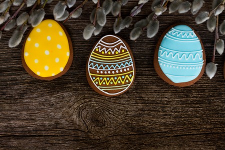 blue, yellow and brown eggs cookies and catkins on wooden background with copy spaceの写真素材