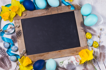 Easter frame with painted blue eggs and flowers and empty blackboard with copy spaceの写真素材