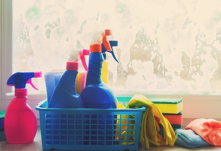 Spring cleaning - container with sprays, gloves and rubbers on windowsill, retro tonedの写真素材