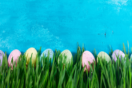 Easter eggs in grass on bright blue wood