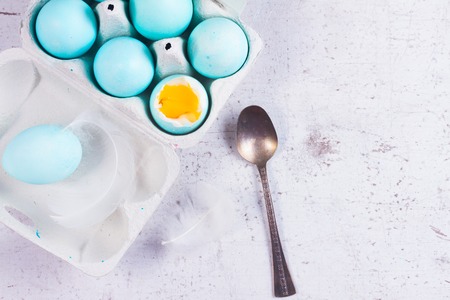 Set of painted blue easter eggs, one with yolk, top view on wooden aged tableの写真素材