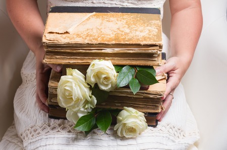 Woman holding old books with white flowers