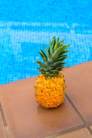 Whole pinapple near pool blue cool waterの写真素材