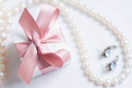 Gift box with pink ribbon with jewellery on white table, top viewの写真素材