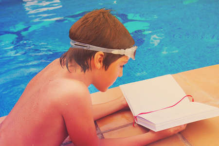 handsome boy reading book near blue pool, close up, retro tonedの写真素材
