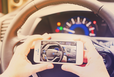 smart car concept - driving wheel and hands holding phone with augmented reality ap, retro tonedの写真素材