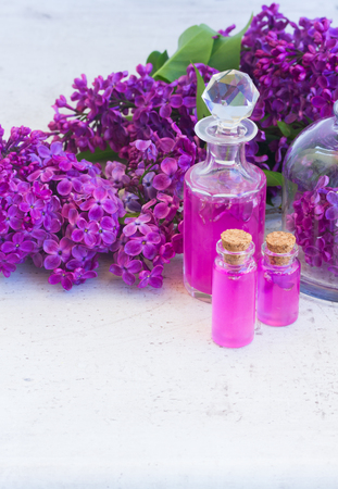 Lilac essence in glass vials and fresh lilac flowers, copy space on wooden tableの写真素材