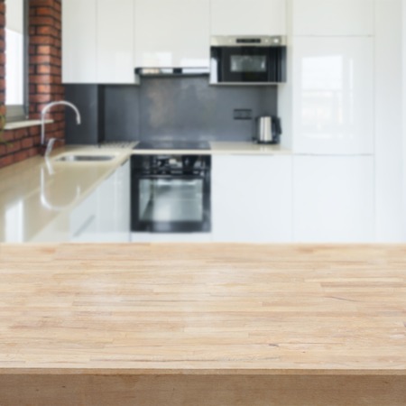 Empty kitchen table top with white modern kitchen in backgroundの写真素材
