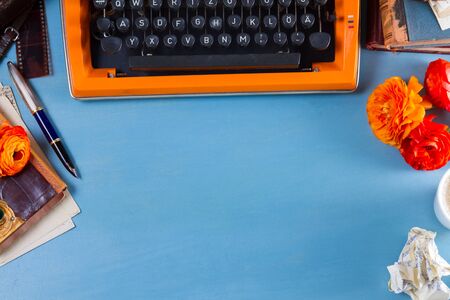 Workspace with orange vintage typewriter, copy space on blue table backgroundの写真素材