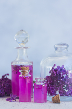 Lilac essence in glass vials and fresh lilac flowers on gray backgroundの写真素材