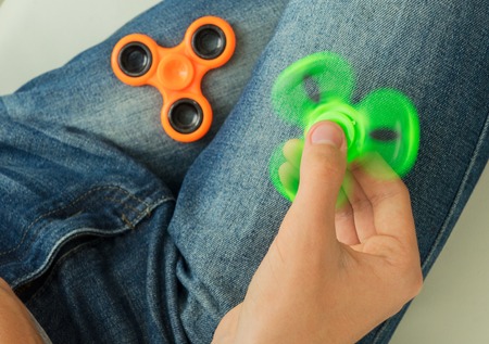 trendy fidget spinner - person holding spinning fidget spinner in hand, close up view