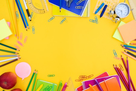 back to school or office styed scene with multicolored school supplies on yellow
