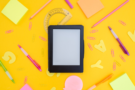back to school or office styed scene with e-book and multicolored school supplies on yellowの写真素材