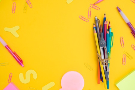 back to school or office styed frame with multicolored school supplies on yellowの写真素材
