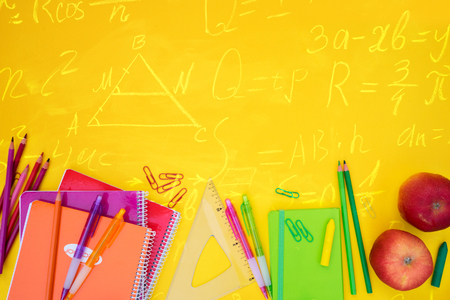 back to school styed scene border with school supplies on yellow with math formulas