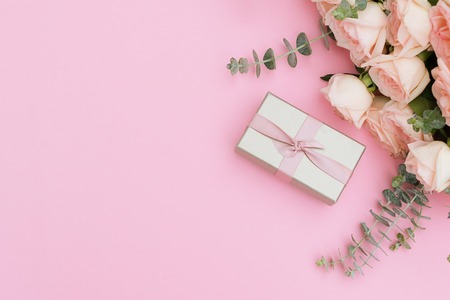 gift or present box and flowers on pink table from above, flat lay frameの写真素材
