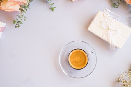 Cup of coffee with gift or present box and flowers on blue table from aboveの写真素材