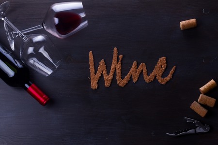 Bottle of red wine and two wine glasses on table with wine word lettersの写真素材