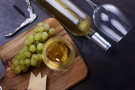 Bottle of white wine and wine glass with grape friut