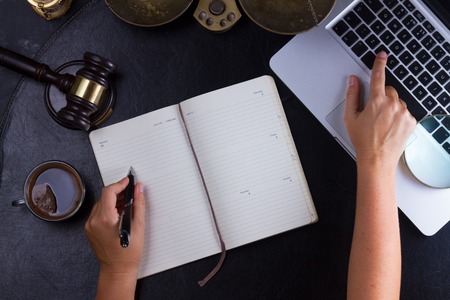 Workspace hero header with law gavel, legal book and laptop keyboard, hands typing and writting in notebook, top view flatlay sceneの写真素材