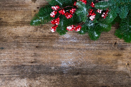twig with red berries and green evergreen tree on aged wooden background with copy spaceの写真素材