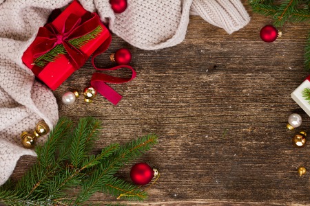 Christmas composition - knitted blanket, evergreen fir tree branches and christmas paper gifts on wooden aged background, flat lay top viewの写真素材