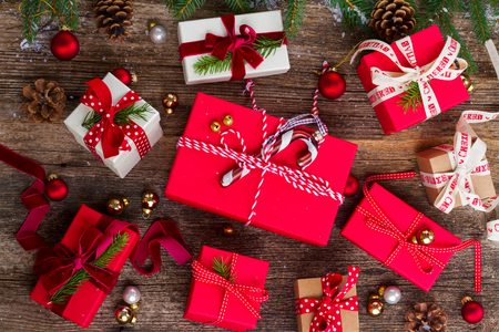 Christmas gift giving - pile of wrapped in red and white paper christmas gift boxes on wooden backgroundの写真素材