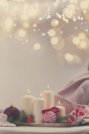 White burning advent candles with christmas decorations with copy space on white leather chairの写真素材