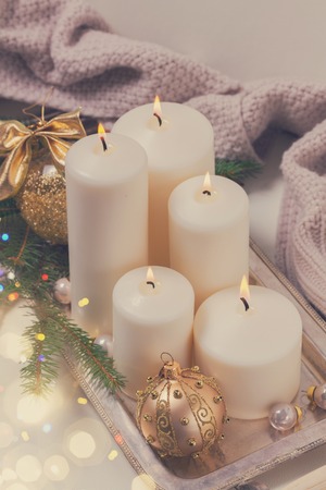 White burning advent candles with christmas decorations and knitted blanket, retro tonedの写真素材