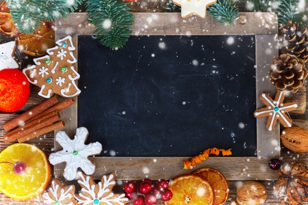 christmas gingerbread cookies with fir tree twigs frame with empty blackboard with snowの写真素材