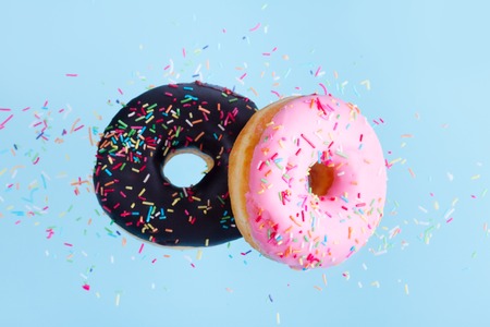 two flying sweet doughnuts with sprincles on blue