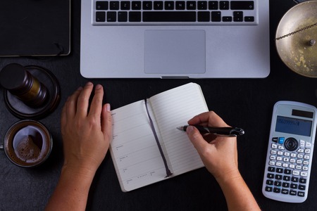 Workspace hero header with law gavel, legal book and laptop keyboard, open empty notebook with someones hands, top view flatlay sceneの写真素材