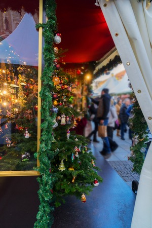 Christmas market kiosk with decorated tree and blurred people in backgroundの写真素材