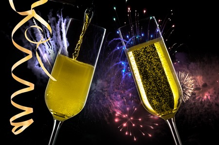 Two festive champagne glasses on black background with fireworks
