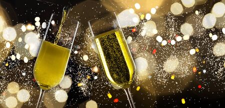 Two festive champagne glasses on black background with golden bokeh lightsの写真素材