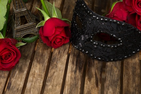 red fresh roses with masque and eiffel tower on wooden tableの写真素材