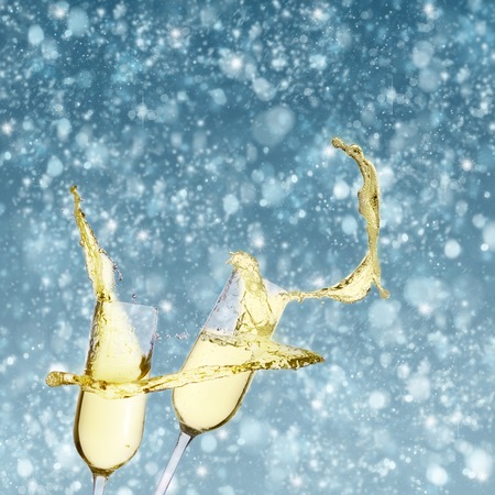Two festive champagne glasses on blue bokeh background with snowの写真素材