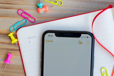 Close up of open notebook and modern phone screenの写真素材