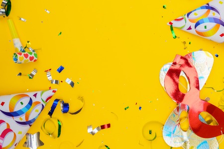 Bright colorful carnival or party scene of confetti and masks on yellow table. Flat lay style, birthday or party greeting card with copy space.の写真素材