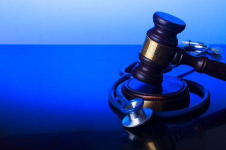 Wooden law gavel with stethoscope on blue - medical law and justice conceptの写真素材