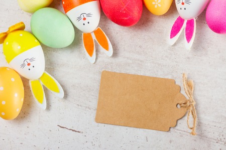 Easter scene with colorful eggs and bunnies, top view with copy space on paper noteの写真素材