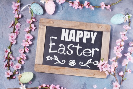 pink cherry blossom twigs frame on gray background, top view easter scene with happy Easter greetingの写真素材