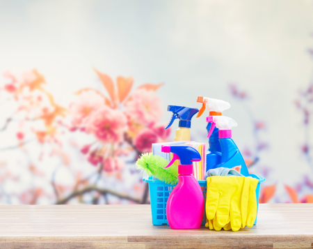 Spring cleaning concept - colorful sprays bottles and rubbers on wood table over spring backgroundの写真素材