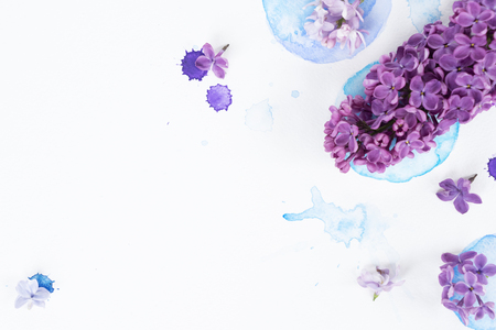 Fresh lilac flowers frame over white background with watercolor paint splashes, flat lay flower composition with copy spaceの写真素材