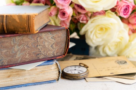 pile of antique books, flowers and clock