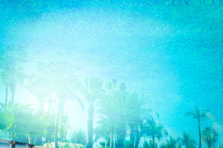 summer background with blue tiled pool with reflections of palm trees toned imageの写真素材